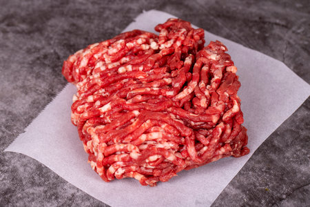 Minced meat on butcher paper. Fresh ground beef on wood background. close up