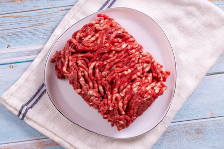 Beef minced on the plate. Fresh ground beef on wood background. Top viewの写真素材