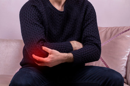 Male elbow pain. People, healthcare and problem concept - close up of man suffering from hand or elbow pain. Painful area highlighted in redの写真素材