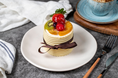 Fruitcake. Strawberry, pear, kiwi and raspberry cake covered with white chocolate on a dark background. Patisserie dessertsの写真素材