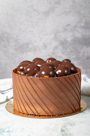 Chocolate covered profiteroles birthday cake. Chocolate cream cake on gray background