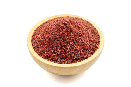 Sumac isolated on white background. Dried ground red Sumac powder spices in wooden bowl