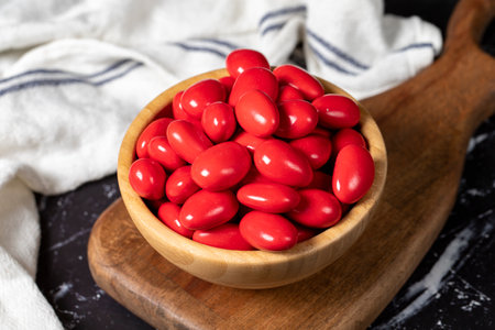 Chocolate and almond dragee. Red chocolate dragee in wooden bowl on dark background