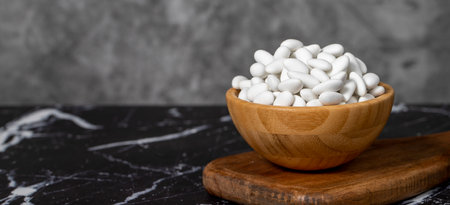Almond Candy. Sugar coated almond candy in wooden bowl on dark background. Small multi-colored...