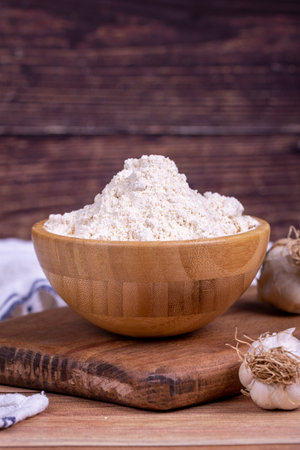 Garlic powder on wooden background. Dried ground garlic powder spices in wooden bowl. close upの写真素材