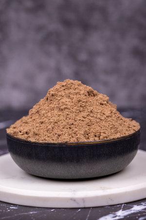 Allspice powder spice on dark background. Powdered dried allspice in bowl. Pimento spice, Jamaican pepper and shavingsの写真素材