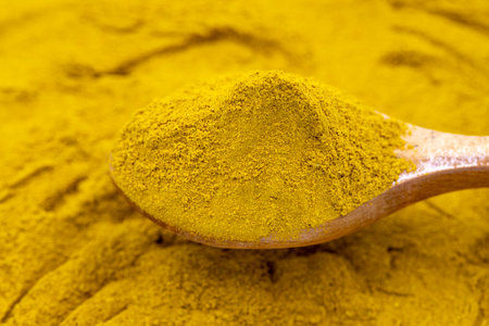 Powdered curry on wooden spoon. Pile of curry powder. close upの写真素材