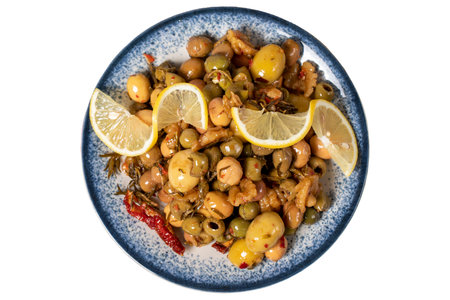 Special mixed olives prepared with green olives, dried red peppers, sun-dried tomatoes, thyme, walnuts and rosemary. Mixed olives with special sauce isolated on white background. Top viewの写真素材