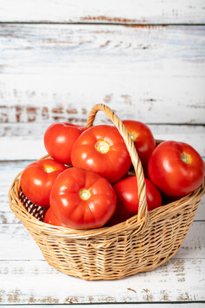 Fresh raw tomato in a basket over wooden background. Tomato harvest season concept. Vegetables for a healthy diet. close upの写真素材