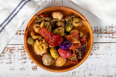 Olive salad at wooden bowl. Mixed olives on a white wood background. Mediterranean food. vegan food. Top viewの写真素材