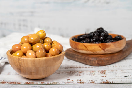 Green and black olives at wooden bowl. Olives on a white wood background. Mediterranean food. vegan foodの写真素材