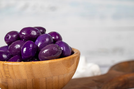 Blueberry fermented olives at wooden bowl. Purple olives on a white wood background. Mediterranean food. vegan food. Copy space. Empty space for textの写真素材