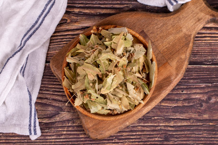Dried linden flowers. Fresh flowers and leaves of linden in wood bowl. herbal medicine. Top viewの写真素材