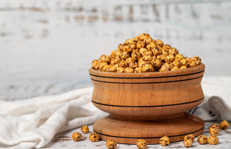 Roasted chickpeas in a wood bowl. Chickpeas on white wood background. Copy space. Empty space for textの写真素材