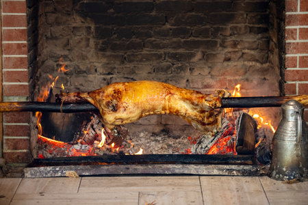 Rotisserie lamb. Whole lamb skewered on a stone stove is cooked over a wood fire. local name lamb...