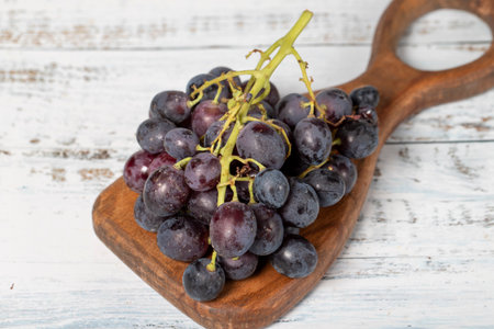 Fresh black grapes on a white wooden background. Organic agricultural products. Delicious bunch of grapesの写真素材