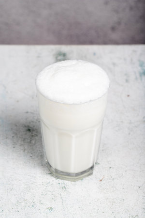 Sparkling buttermilk. Close-up. A glass of ayran on a gray backgroundの写真素材