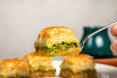 Pistachio baklava. Turkish and Arabic cuisine delicacies. He is holding a slice of baklava with a fork. Close upの写真素材
