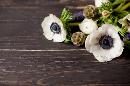 White and violet flowers lying on the old, dark, wooden deskの写真素材