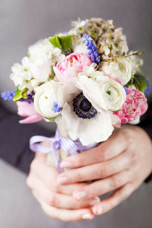 Woman in grey dress and black shirt is holding in her hands a spring bouquetの写真素材
