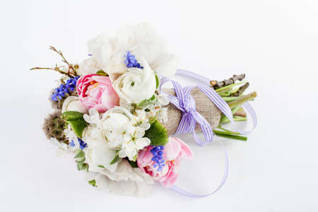 Bouquet from pink tulips, violet grape hyacinths, white anemones, violet veronica and white buttercup with violet ribbon lying on white backgroundの写真素材