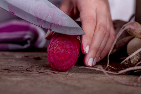 Cook is cutting a beetroot with knifeの写真素材