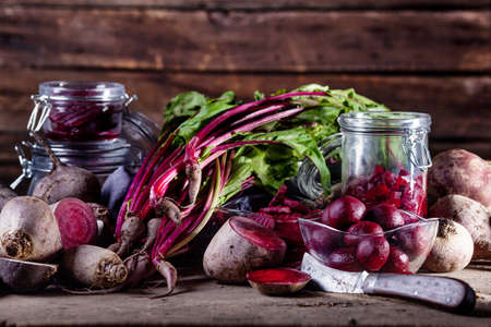 Beetroots in slices, balls, chips and fresh beet leaves with old knifeの写真素材