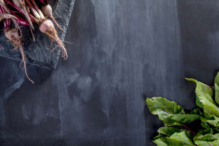 Bunch of beetroots on the stone and blackboard with space to writeの写真素材