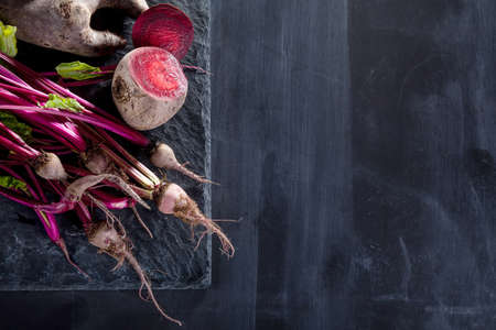 Bunch of beetroots on a black stone and blackboardの写真素材