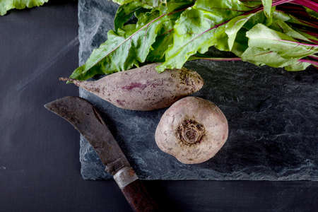 Bunch of beetroots on the stone and blackboard with old style knifeの写真素材