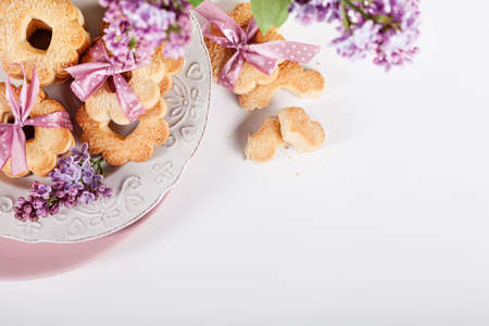 Cookies with pink ribbons on a white plate with lilac flowersの写真素材