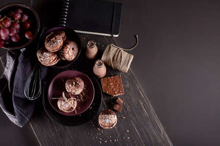 Italian maroni cookies on the plate and bowl with grapes, chocolate milkshakes, cloth, notebook on dark old wooden background, top viewの写真素材