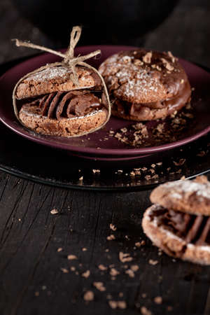 Italian maroni cookies with pieces of chocolate on old wooden background and platesの写真素材