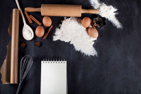 Ingredients like eggs, flour, cinnamon, anise, rolling pin, paper on blackboard