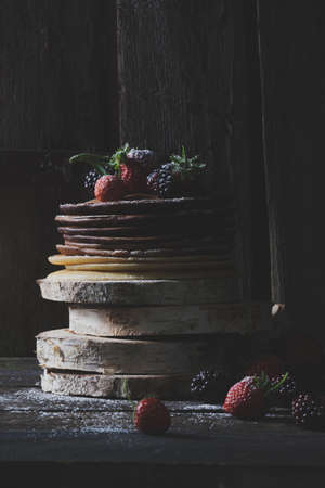 Rustic pancakes with organic fruits on wooden blocks with old wooden doors in backround