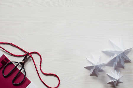 Three paper Christmas trees and scissors on white wooden deskの写真素材