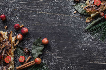 Christmas tart with small apples, cinnamon, anise and sugar on black wooden tableの写真素材