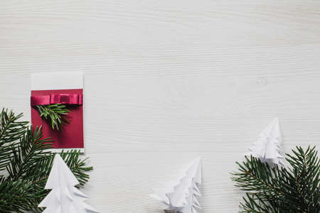 Christmas label and green decorations on white wooden table with origami treesの写真素材