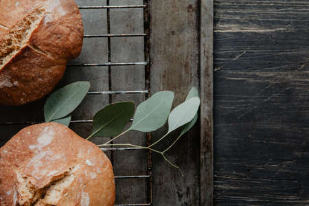Homemade bread on a cooling rack and old metal tray, on wooden tableの写真素材
