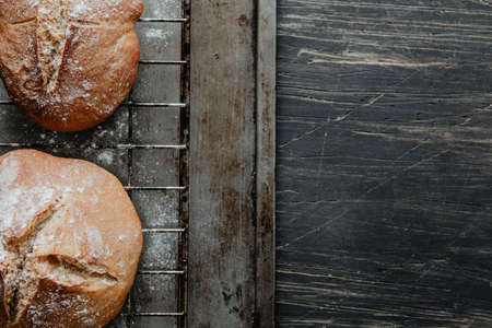 Freshly baked bread lying on cooling rack and scratched wooden tableの写真素材
