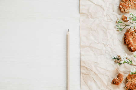 Healthy oat cookies on the white wooden table with paper, pencil and little flowersの写真素材