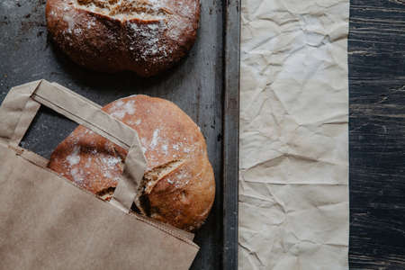 Homemade rustic bread on a baking tray with flour, flat layの写真素材