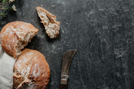 Traditional irish soda bread for St. Patrick's Day with little flowers and old knife on black stoneの写真素材