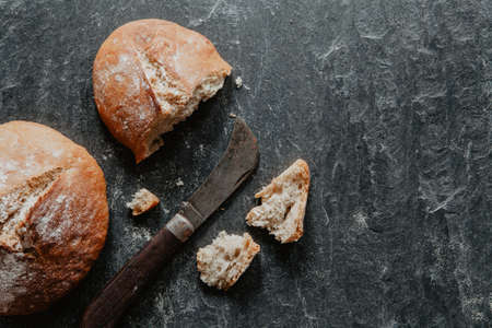 Homemade loaf of Irish soda bread with raisins on black stone with knifeの写真素材