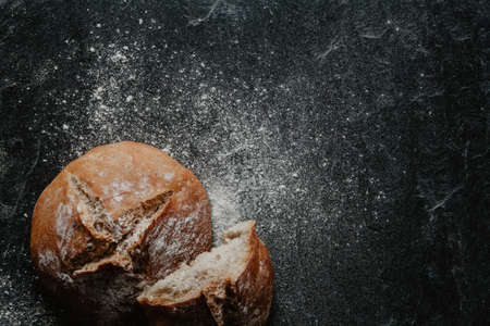 Freshly baked bread with flour on black stoneの写真素材