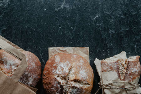 Healthy bread freshly from oven with packing paper on dark stoneの写真素材