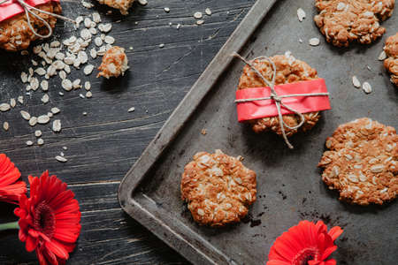 Gluten free biscuits with red paper and flowers on the side of black, vintage tableの写真素材