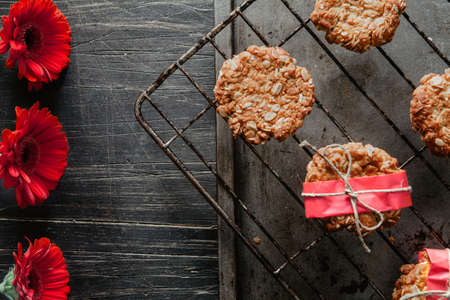 Anzac cookies on a cooling rack with red flowers on the side の写真素材