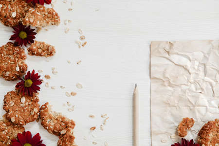 Anzac cookies on the vintage white wood with flowers, paper and pencilの写真素材