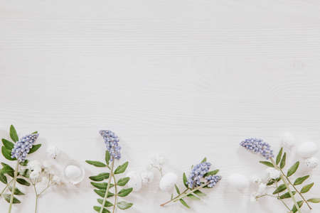 White and green Easter decoration with grape hyacinths, leaves and little eggs on white woodの写真素材